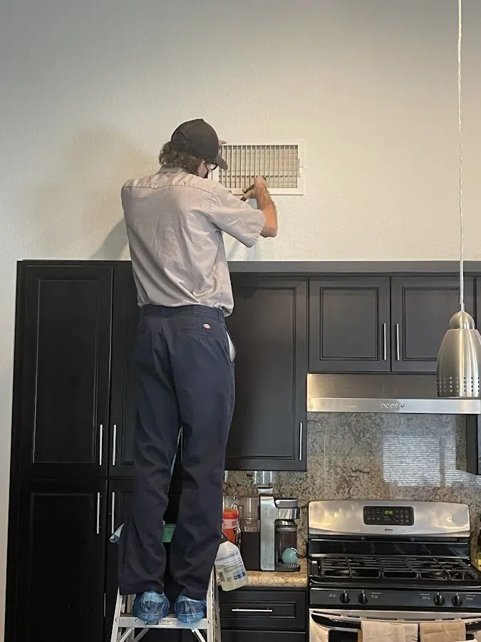 Technician inspecting an air vent during HVAC service in St. Cloud